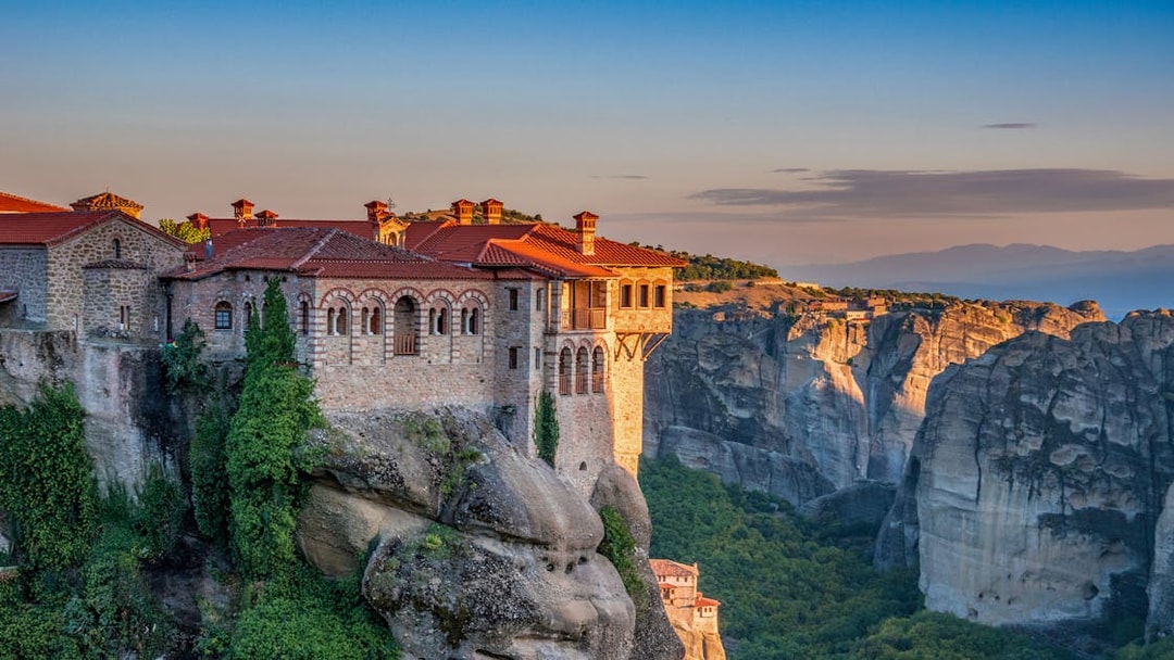 Meteora monastery perched on a cliff at sunset during Athens to Meteora full-day trip.