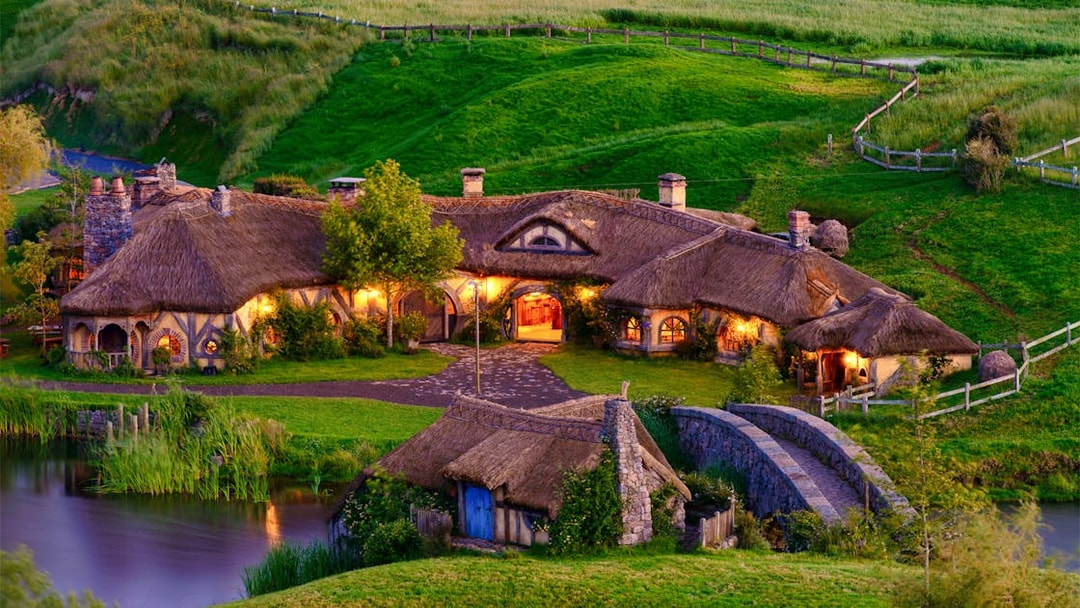 Hobbiton village with thatched cottages and stone bridge, part of Rotorua tour.