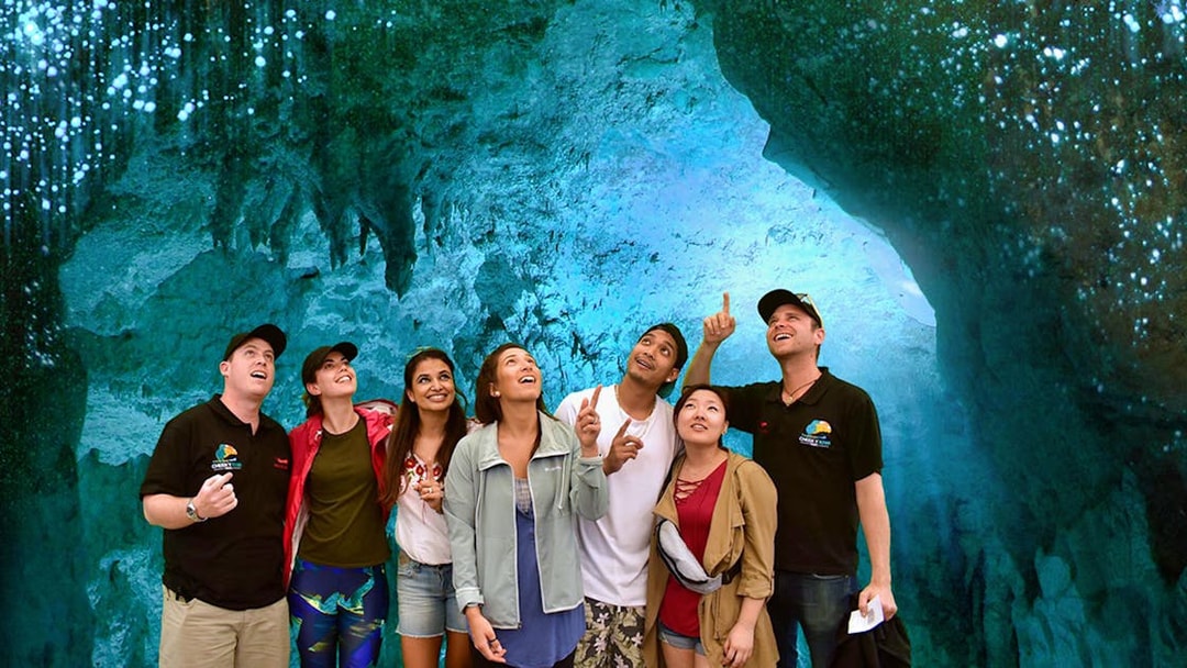 Group exploring glowworm-lit Waitomo Caves on Auckland tour.