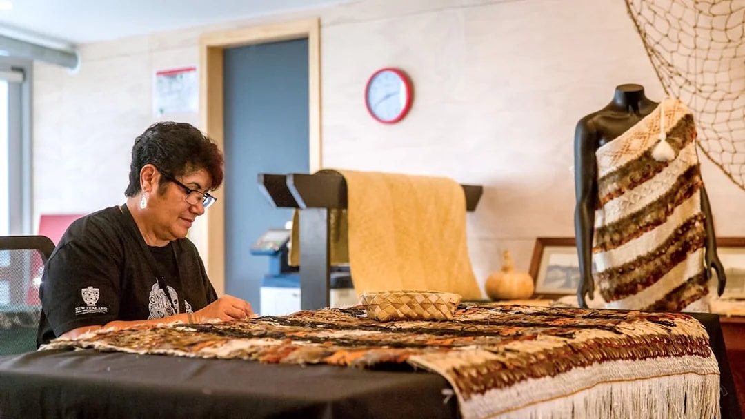 Craftsperson weaving traditional Māori garment at Te Puia, New Zealand.