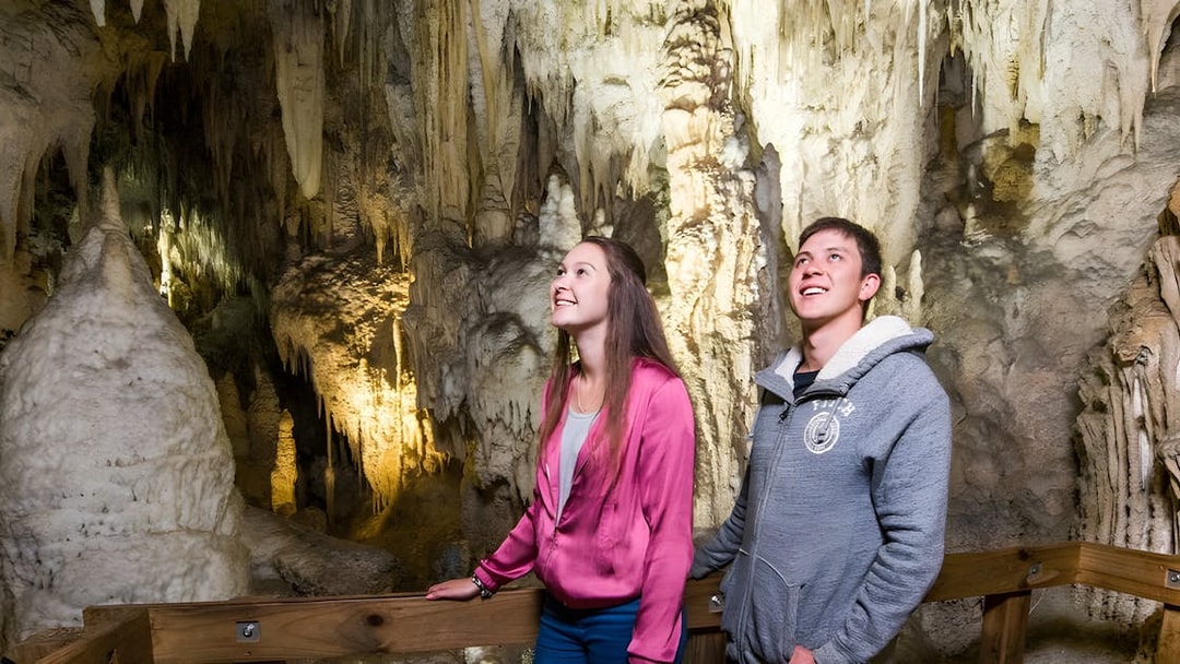 Visitors exploring Waitomo Glowworm Caves in Auckland, viewing stalactites and stalagmites.