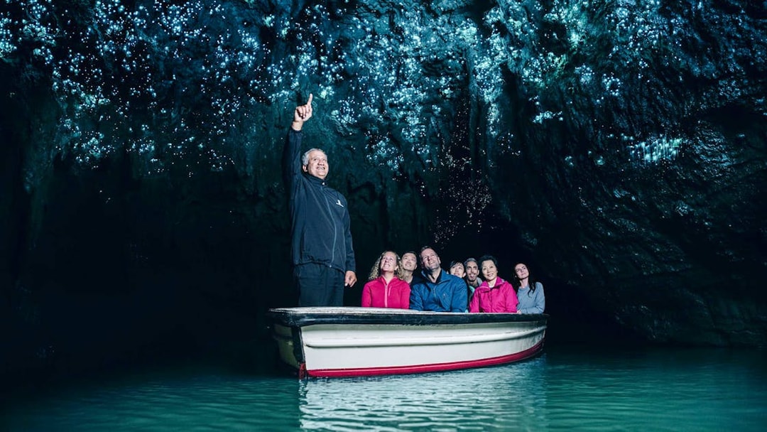 Tourists on a boat admire glowworms in Waitomo Caves, Auckland.
