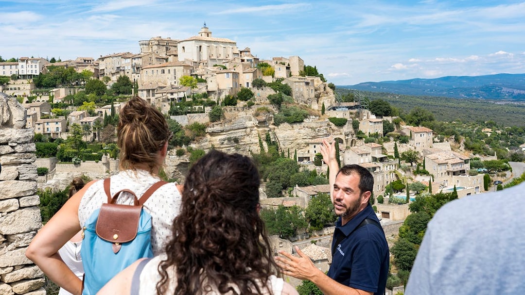 Tour guide explaining the view of Gordes village in Provence to visitors.