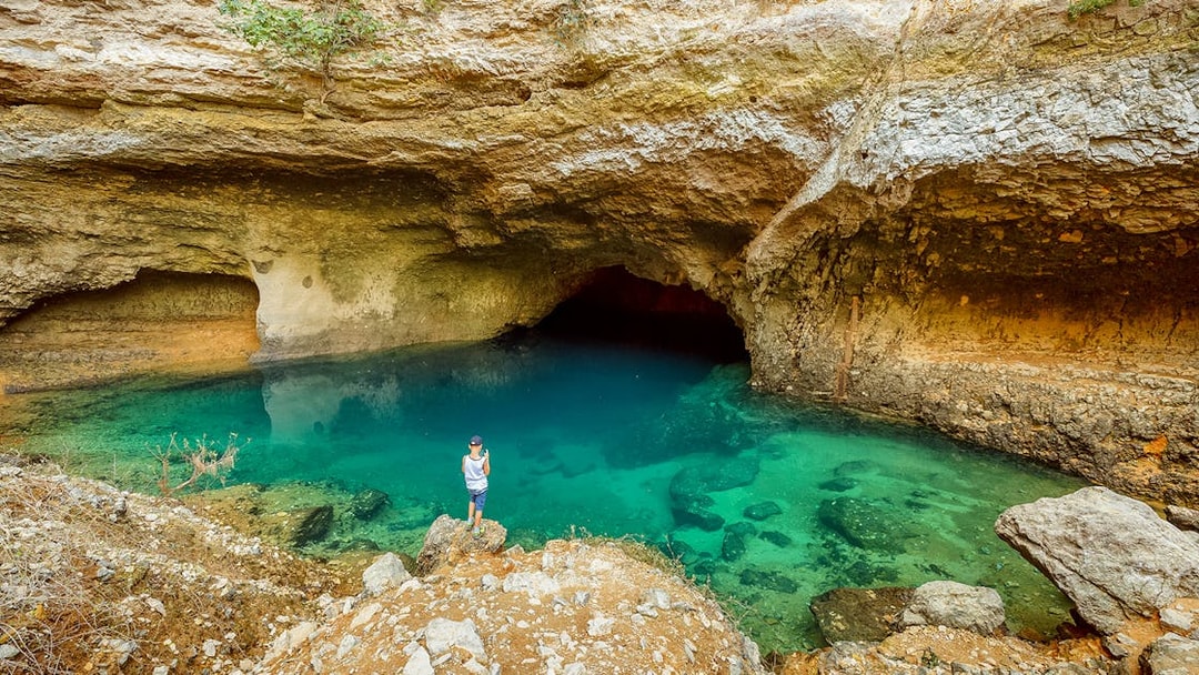 Cave with turquoise water and rocky surroundings in Provence, part of a guided tour from Avignon.