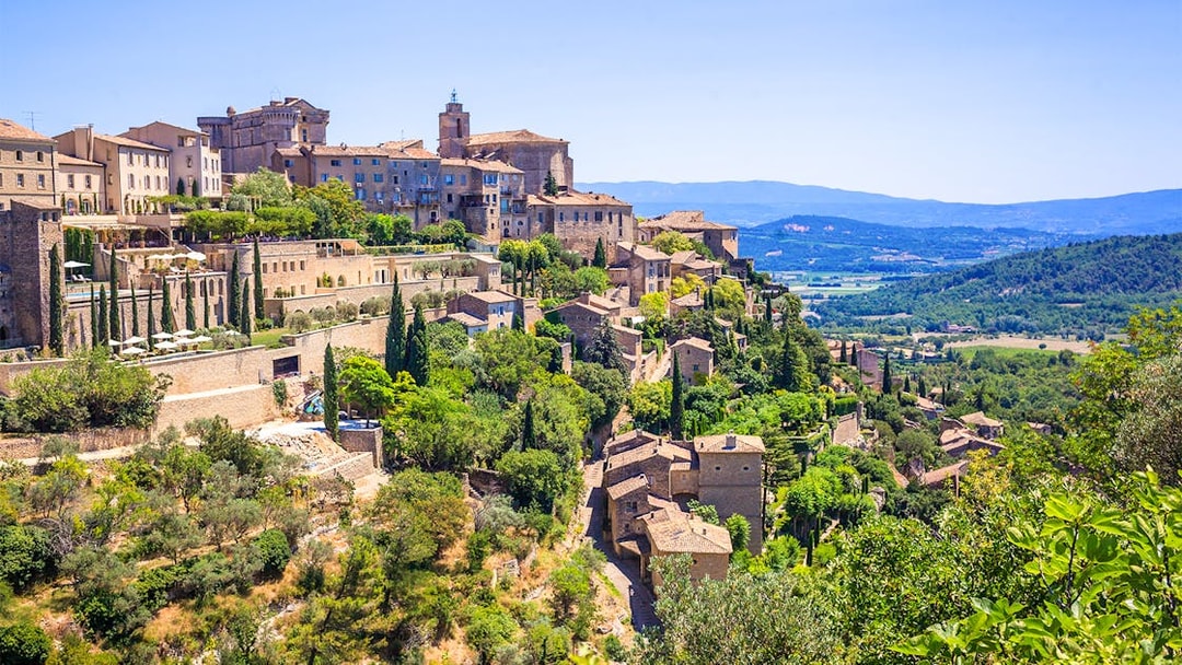 Hilltop village of Gordes in Provence with stone buildings and lush greenery.