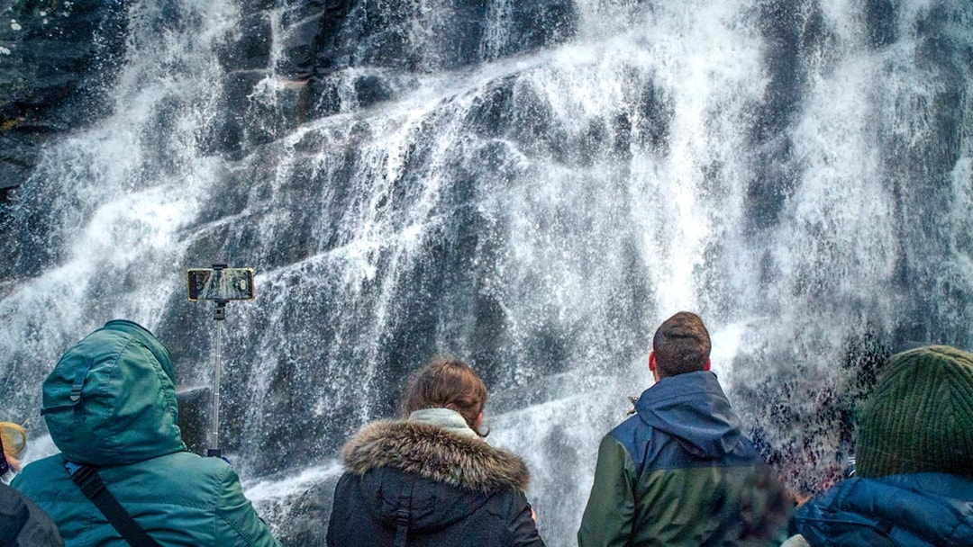 Visitors viewing a waterfall during the Mostraumen Fjord Cruise from Bergen.