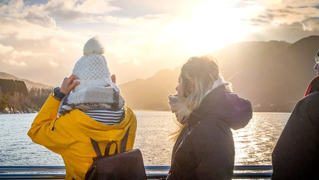 People enjoying the Mostraumen Fjord Cruise from Bergen, with scenic mountain views.