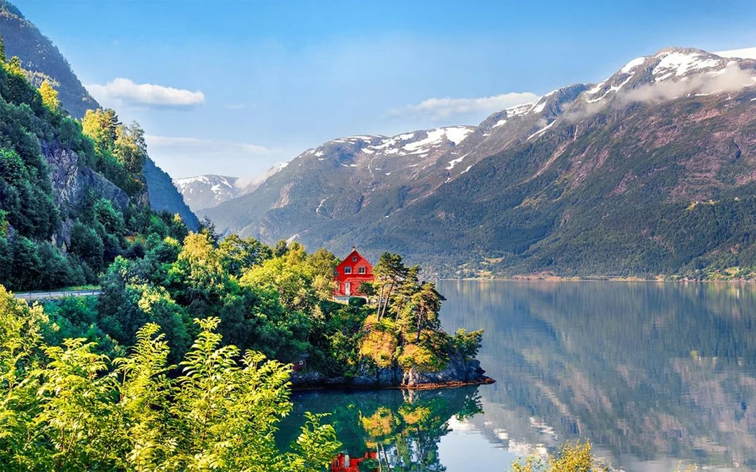 Small village house by Hardangerfjorden with surrounding mountains and lush greenery.