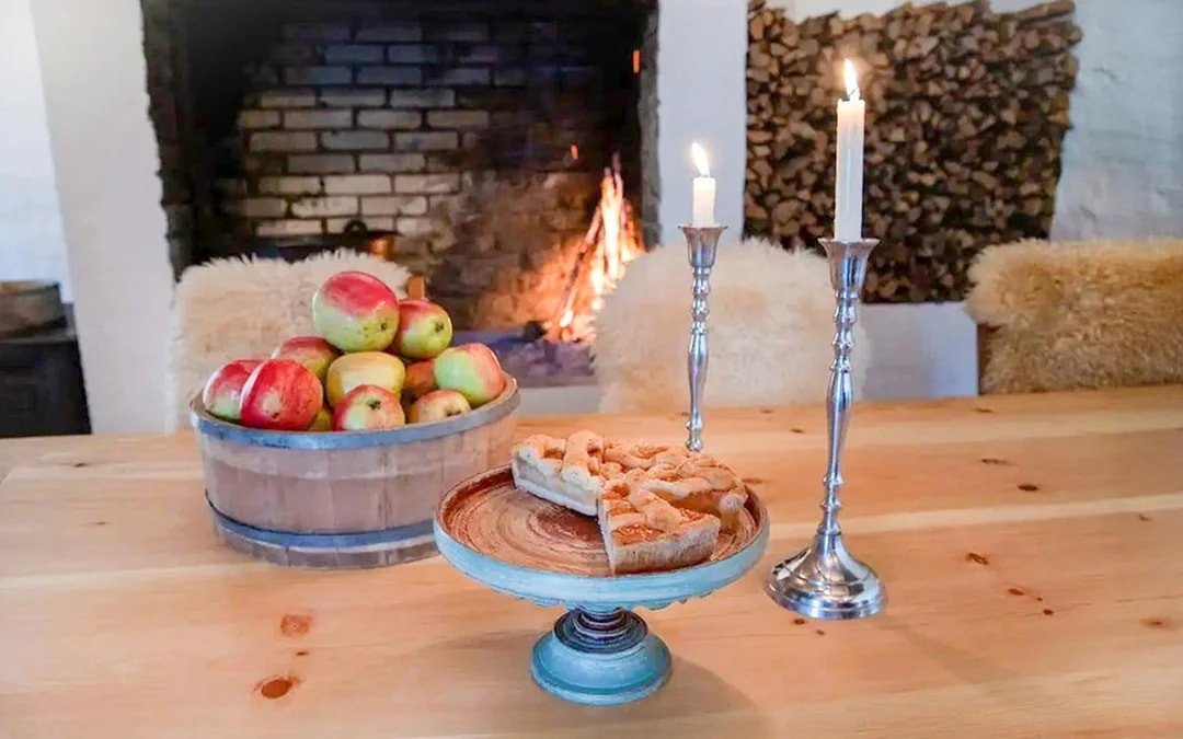 Apples and apple cake on a table by a fireplace at Spildegarden farm.