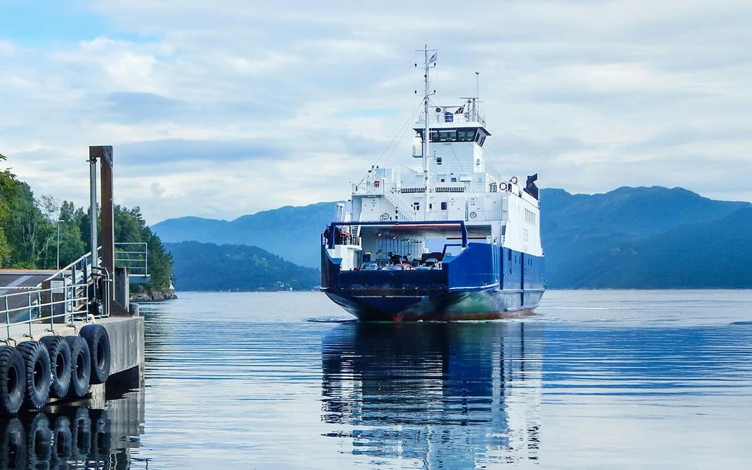 Ferry approaching dock on Hardangerfjord with mountains in the background.
