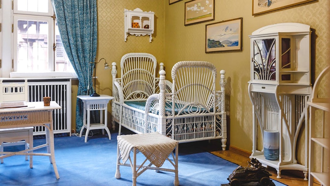 Luxurious room with wicker bed, desk, chairs, and bookshelf at Peles Castle.