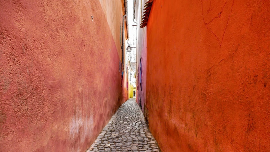 Narrow cobblestone alley of Rope Street, Brasov with colorful walls.