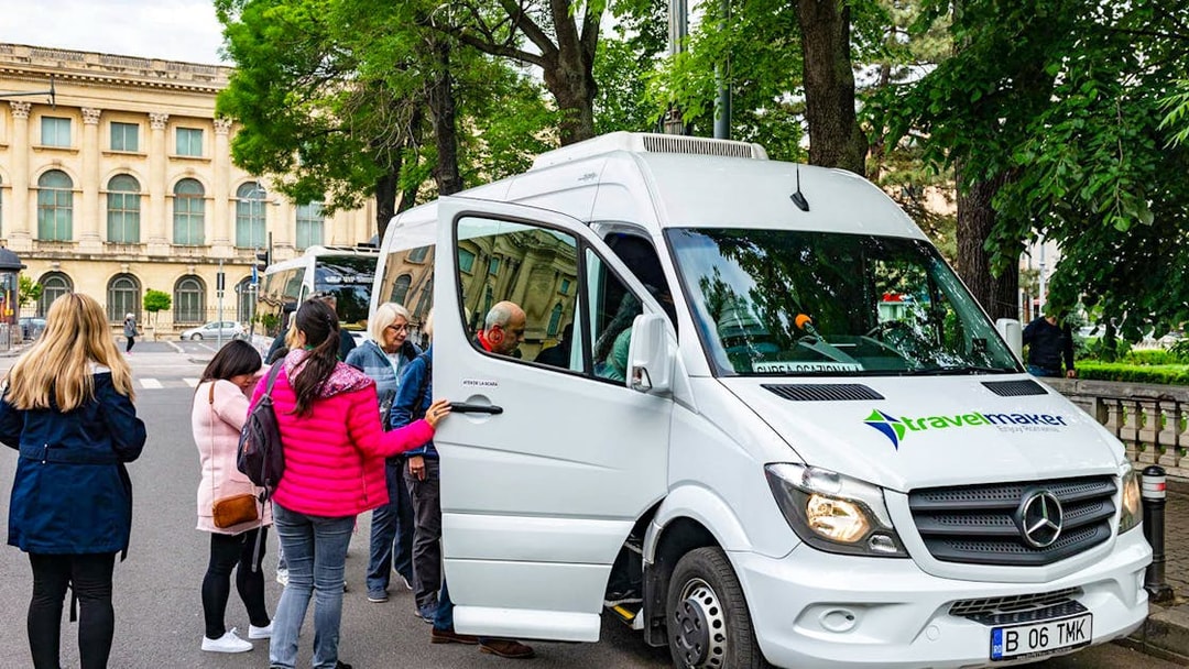 Visitors boarding AC transfer bus for full-day tour to Dracula’s Castle, Peles Castle, Brașov.