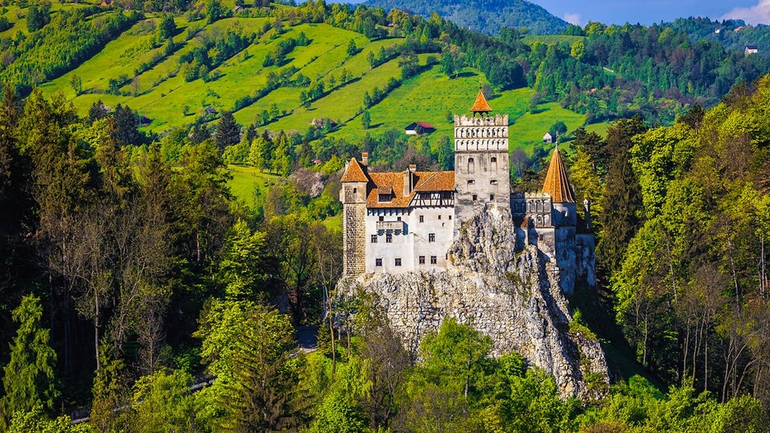 Bran Castle exterior surrounded by lush green hills in Transylvania, Romania.