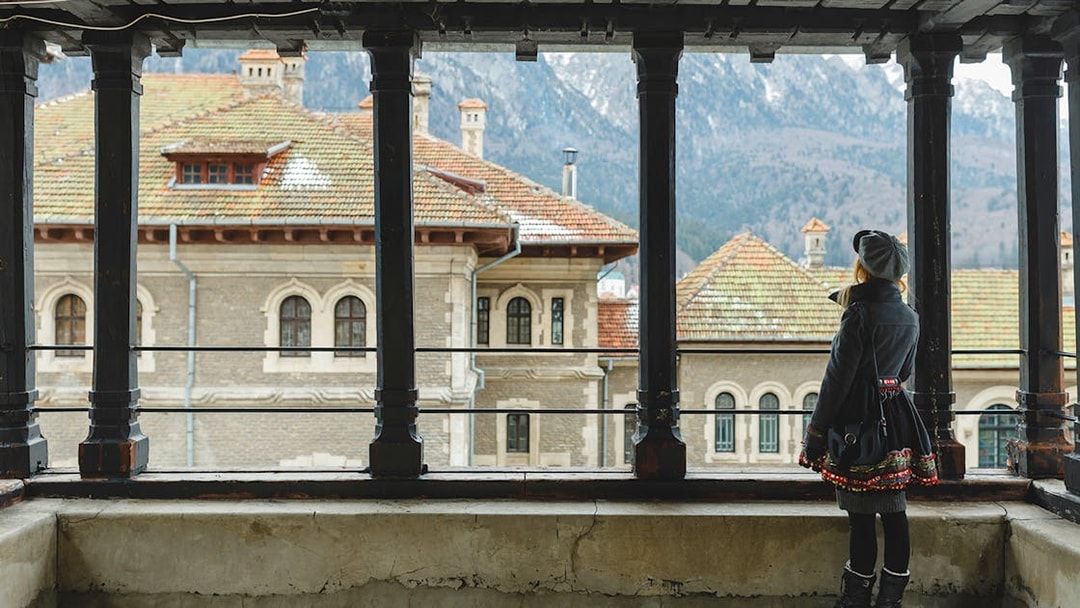 Guest viewing Peles Castle courtyard through window, Sinaia, Romania.