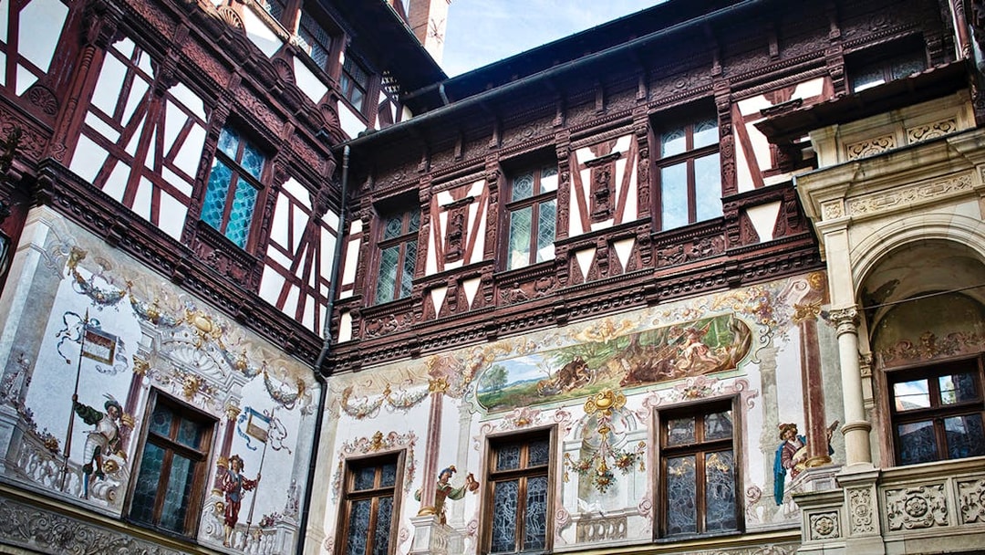 Peles Castle wall details with intricate frescoes and ornate woodwork.