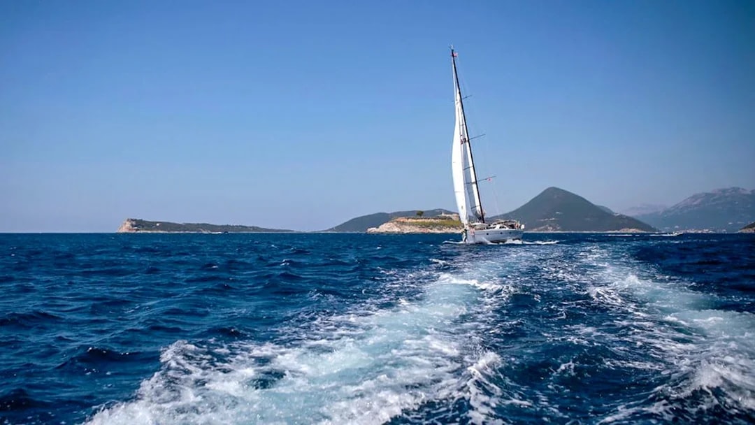Sailboat on Adriatic Sea during Kotor Boat Tour with mountains in the background.