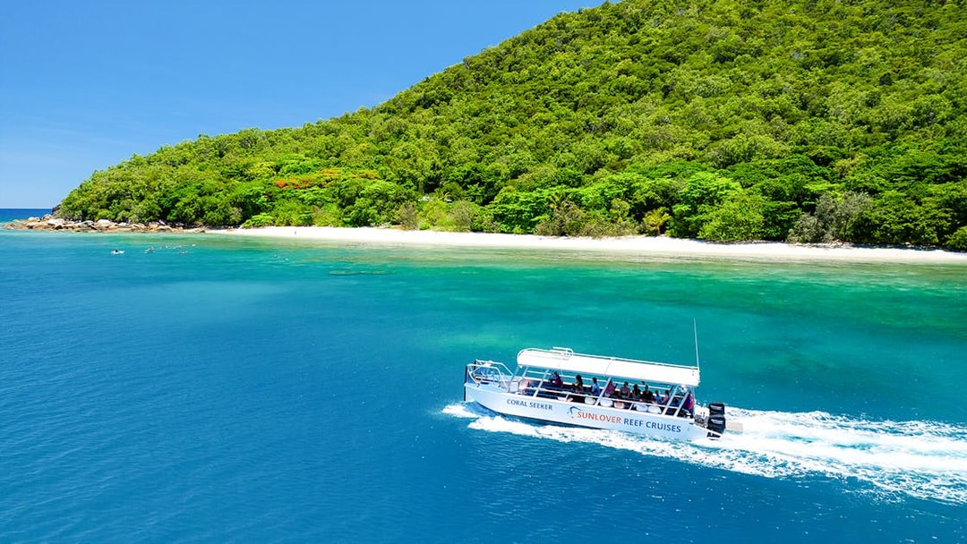 Glass bottom boat near Fitzroy Island, Australia, with lush greenery and clear blue water.