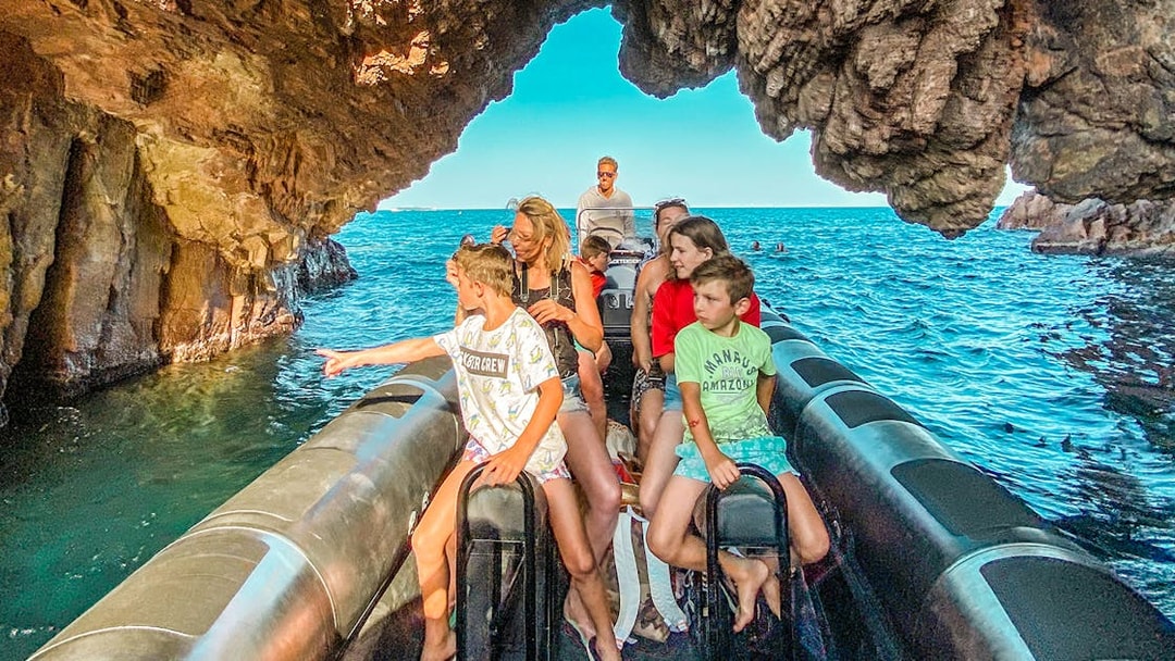 Family on boat tour exploring Esterel National Park's hidden coves.