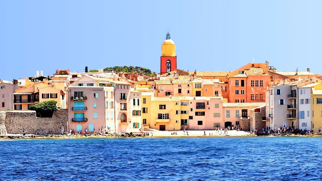 Colorful buildings and church tower along the waterfront in Saint Tropez, France.