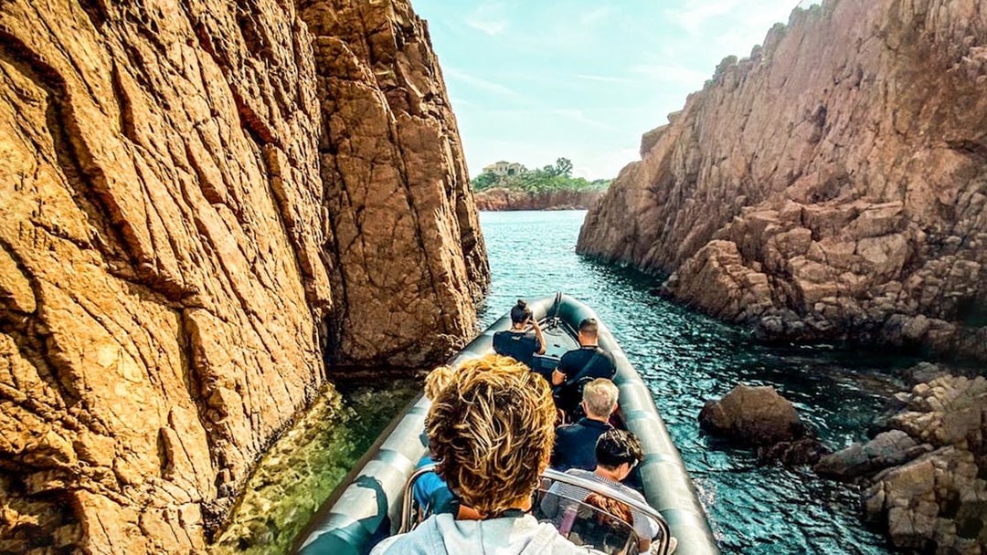 Boat navigating between rocky cliffs in Estérel Natural Park near Cannes.