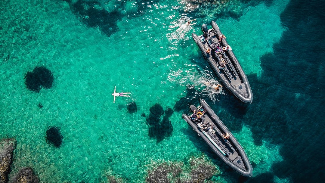 Guided boat tour in Estérel Natural Park, Cannes, with people swimming in clear blue water.