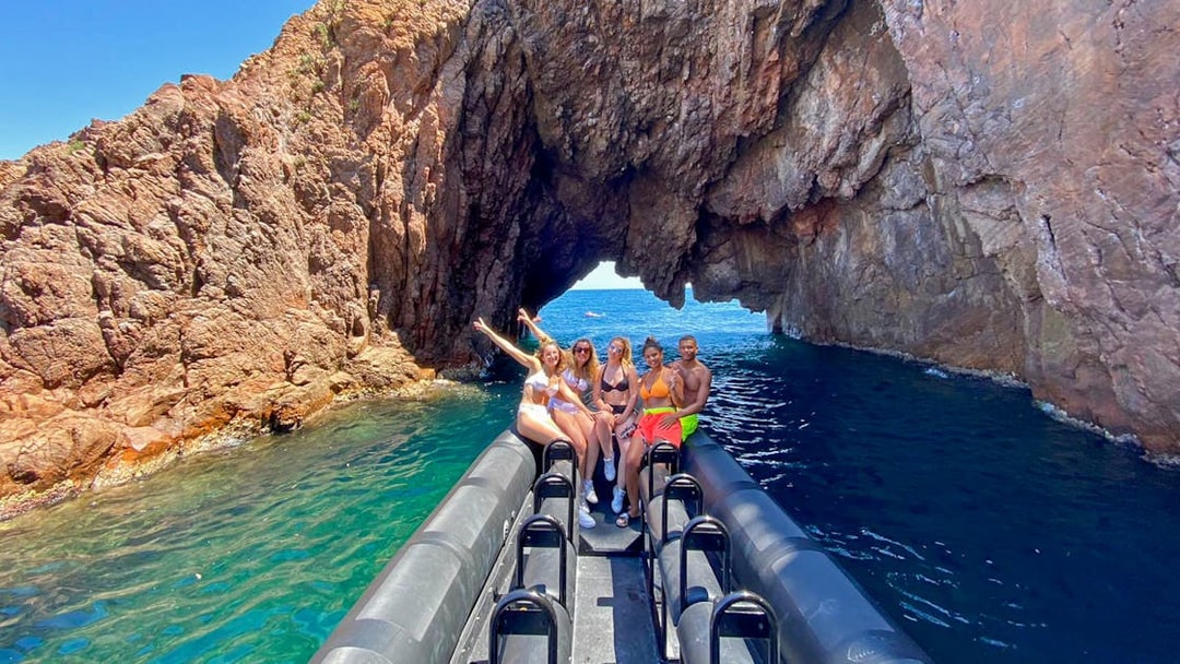 Boat tour group exploring rocky arch in Estérel Natural Park, Cannes.