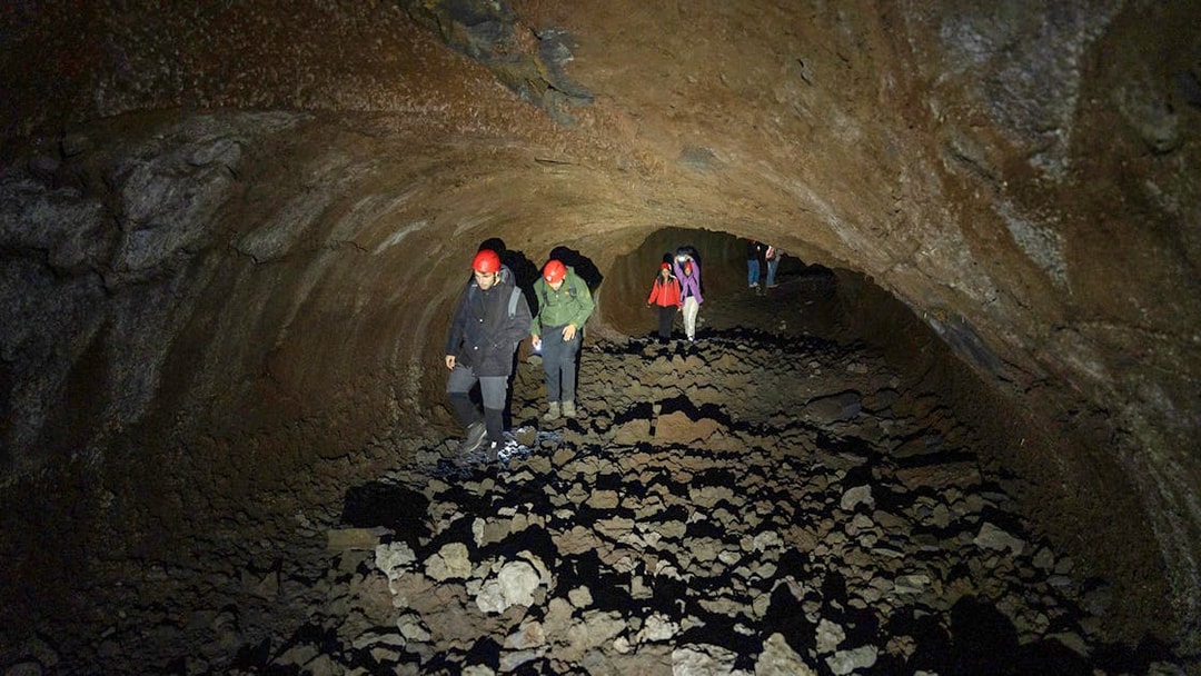 Tourists exploring a lava cave during the Etna Morning Tour in Catania.