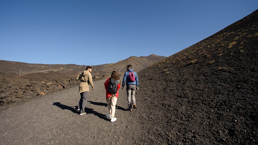 Group hiking on volcanic terrain during Half-Day Etna Jeep Tour.