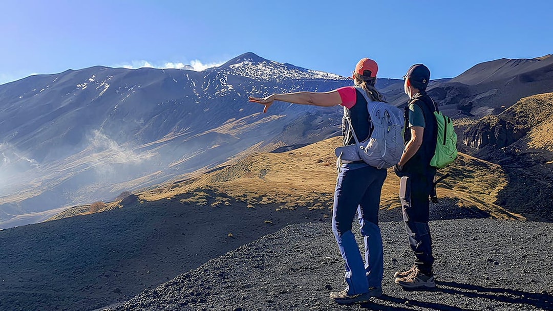 Hikers pointing towards Mount Etna during an afternoon guided tour.