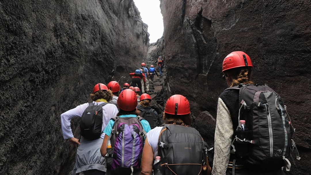 Hikers with helmets navigating narrow rocky path at Mount Etna.