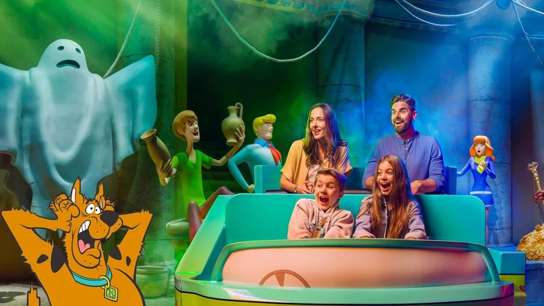 Visitors on a Scooby-Doo ride at Warner Bros. World™ Abu Dhabi, surrounded by animated characters.