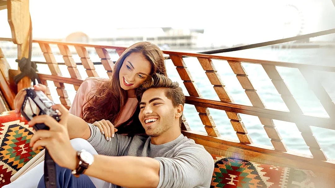 Couple taking a selfie on an abra boat during a Dubai Canal sightseeing tour.