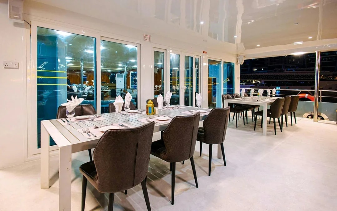 Dining area setup on Alexandra Sea Lounge Dhow Cruise with tables and chairs.