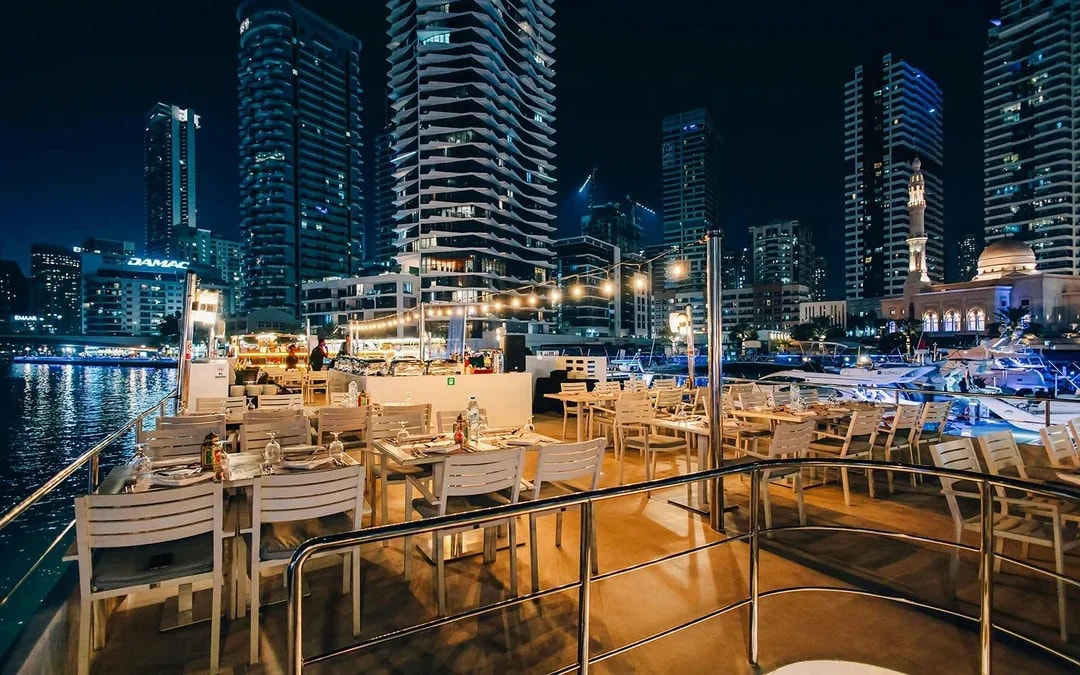 Seating area on Alexandra Sea Lounge Dhow Cruise with city skyline at night.