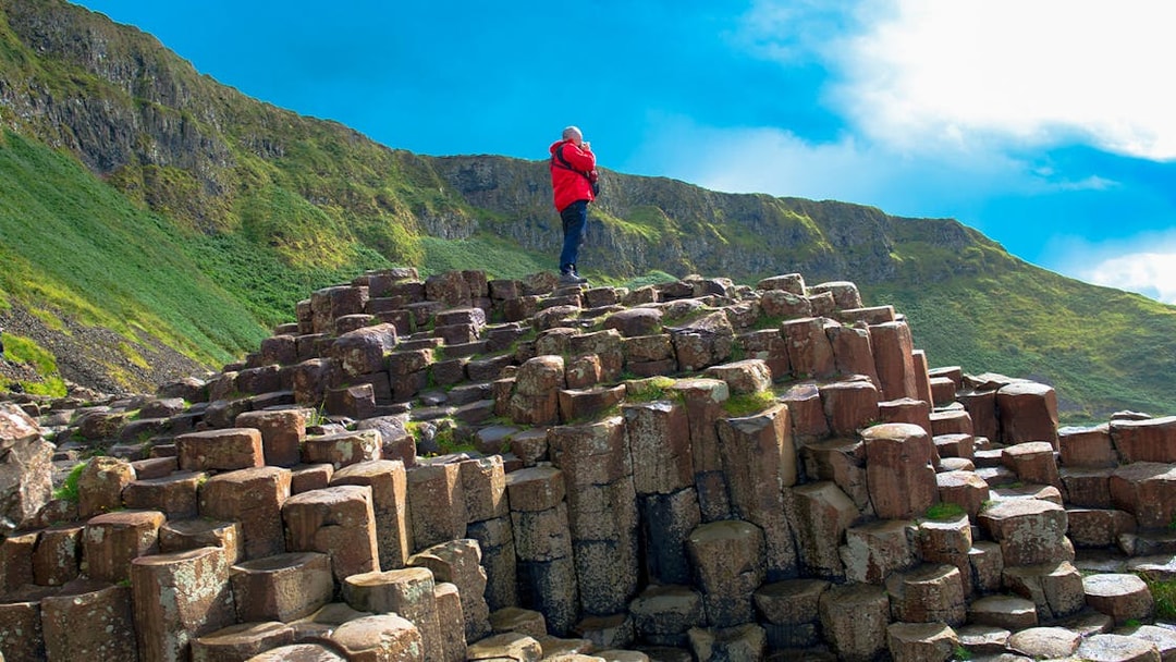 Man standing on basalt columns at Giant's Causeway trail, Northern Ireland.