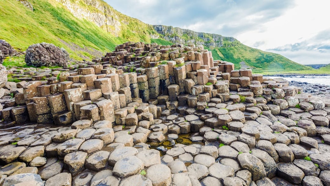 Giant's Causeway basalt columns with green cliffs in Northern Ireland.