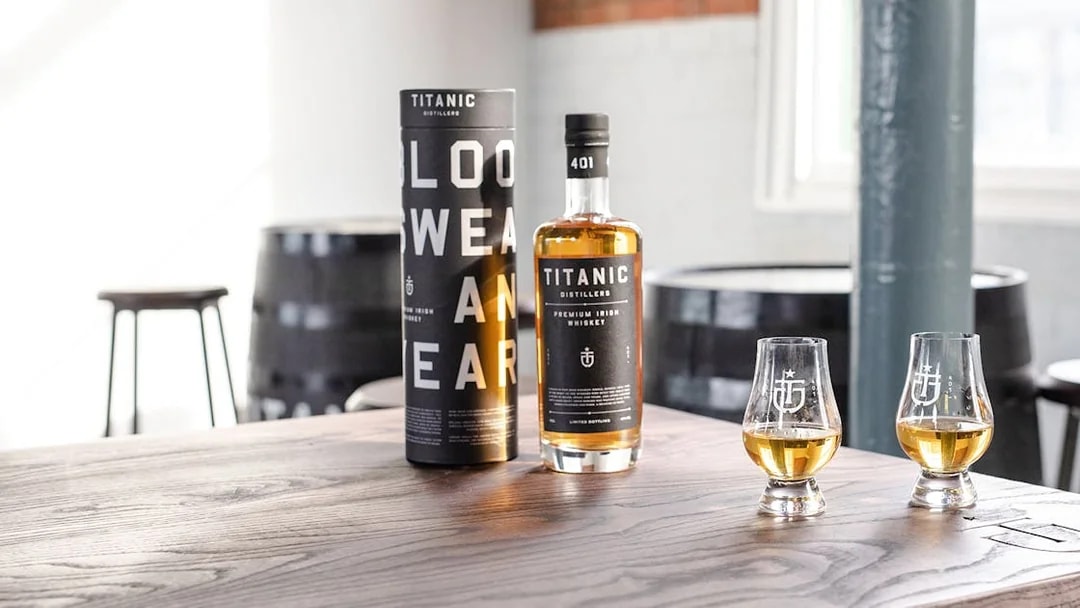 Titanic Distillers whiskey bottle and glasses on a wooden table for tasting experience.