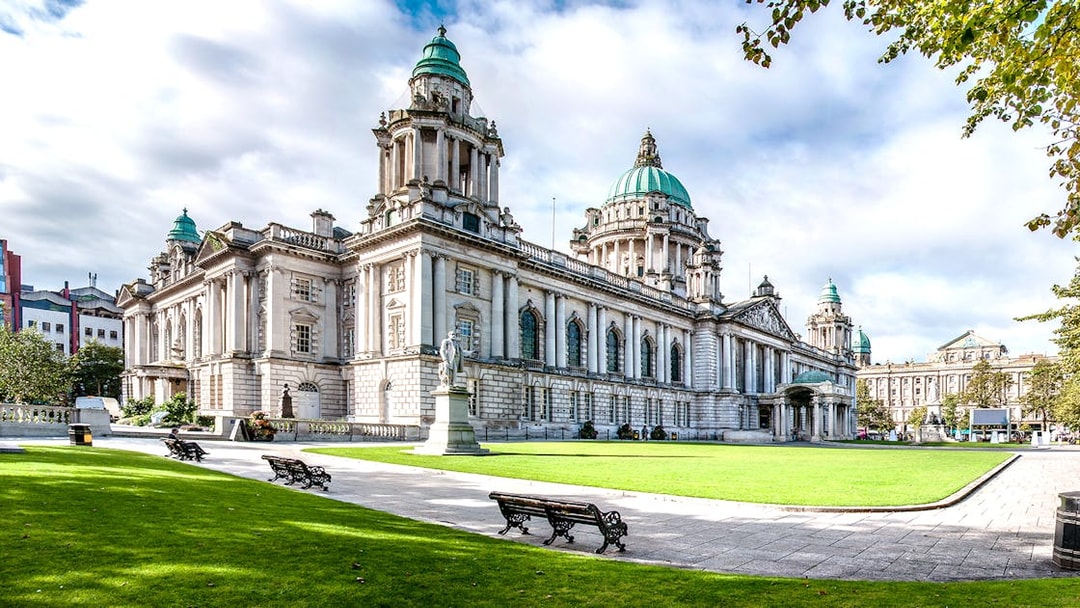 Belfast City Hall with green domes and surrounding gardens, part of Dublin to Giants Causeway tour.