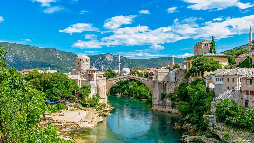 Stari Most bridge over Neretva River in Mostar, Bosnia and Herzegovina, with surrounding historic buildings.