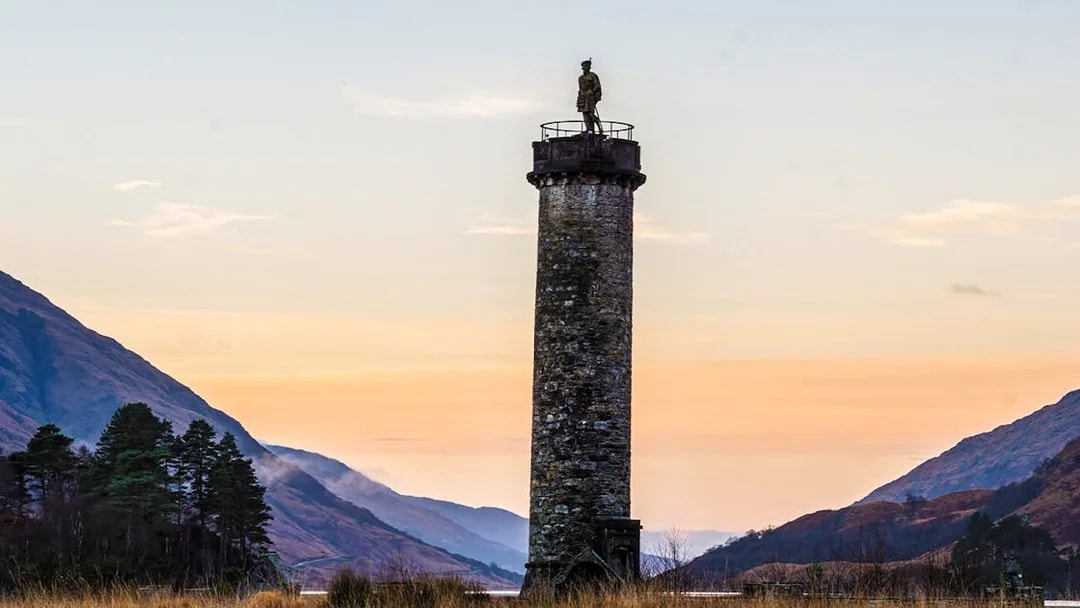 Glenfinnan Monument at sunset with surrounding hills, Scotland.