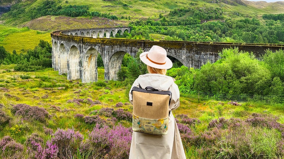 Guest standing near Glenfinnan Viaduct in Scotland, surrounded by lush greenery.