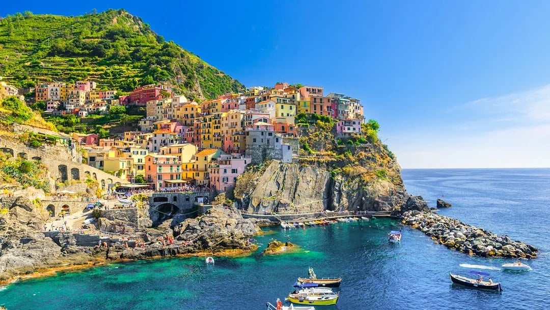 Colorful cliffside village of Manarola in Cinque Terre, Italy, with boats in the harbor.