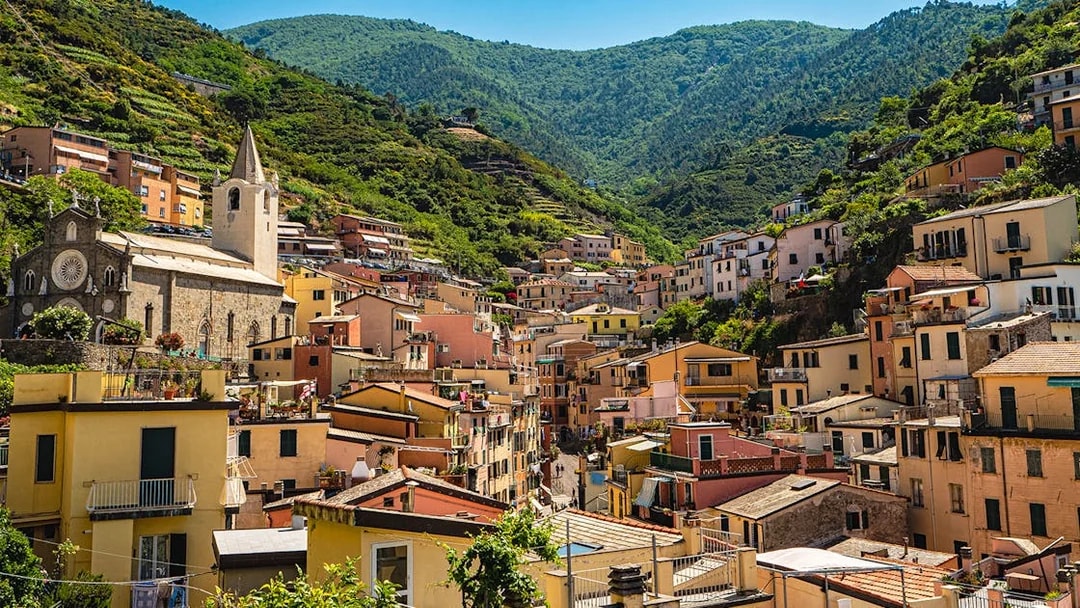 Colorful hillside village in Cinque Terre with church and terraced houses.