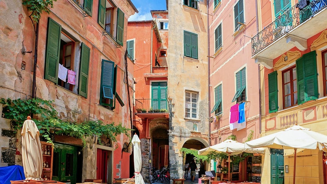 Colorful buildings and outdoor cafes in a narrow street of Cinque Terre, Italy.