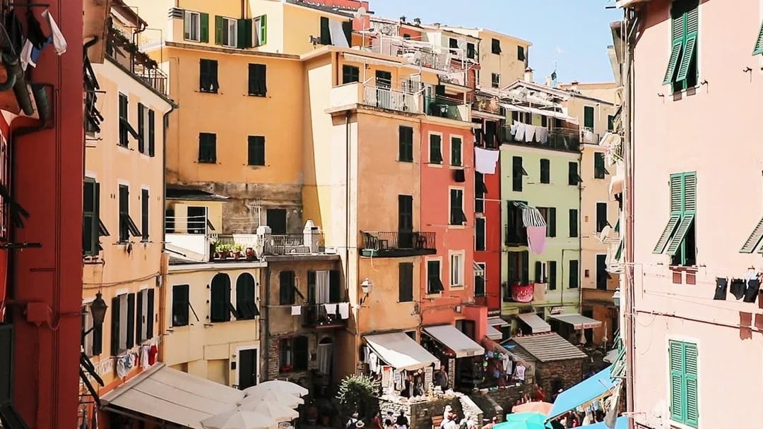 Colorful buildings in Vernazza, Cinque Terre, with tourists exploring the narrow streets.