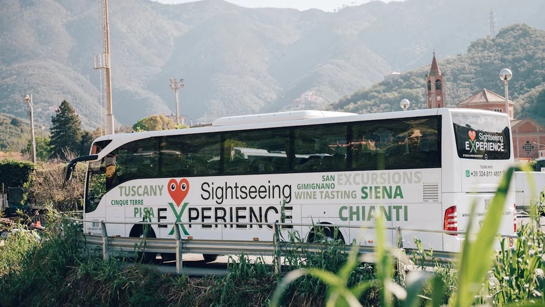 Sightseeing bus in Cinque Terre with mountain backdrop, promoting Tuscany and Siena tours.