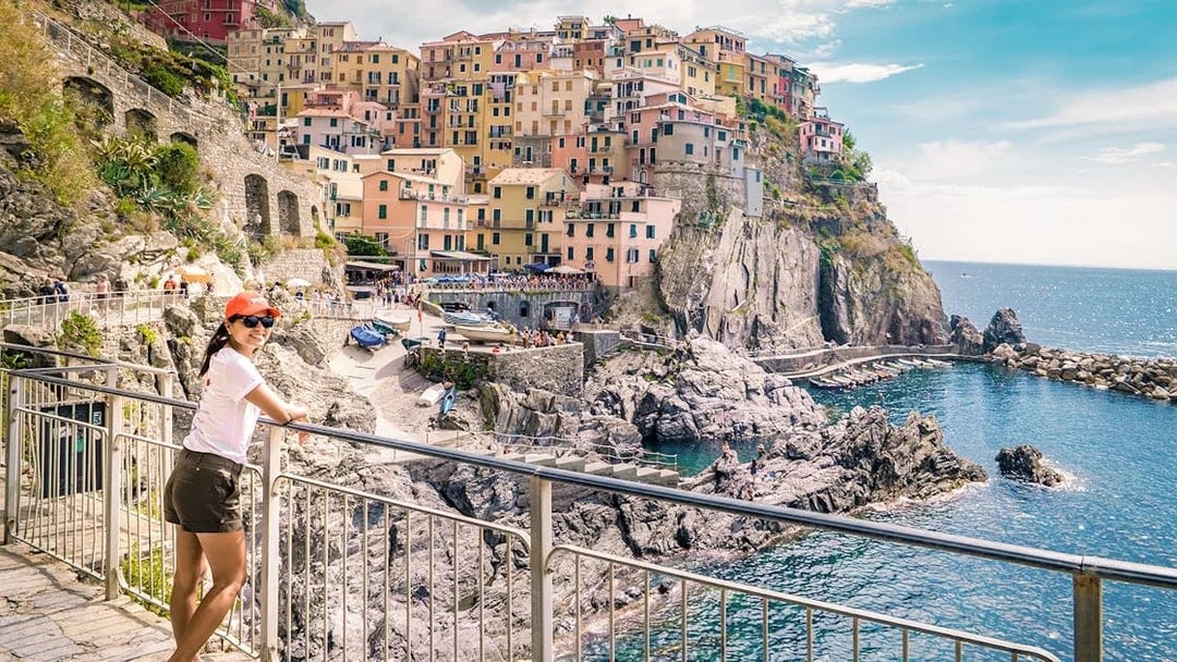 Person enjoying the view of colorful cliffside buildings in Manarola, Cinque Terre.