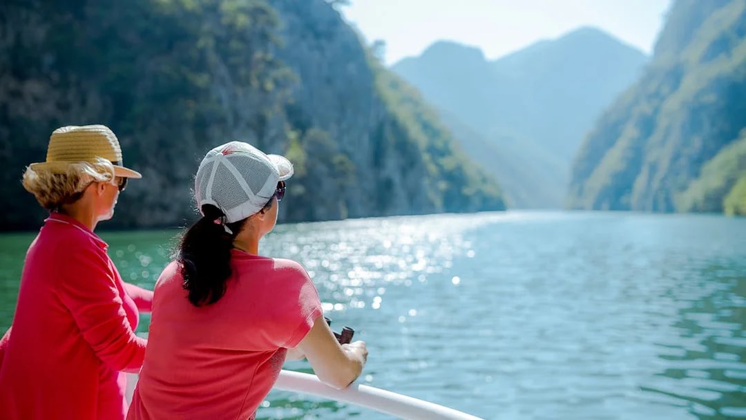 Tourists enjoying a boat ride with scenic views of Cinque Terre cliffs and water.