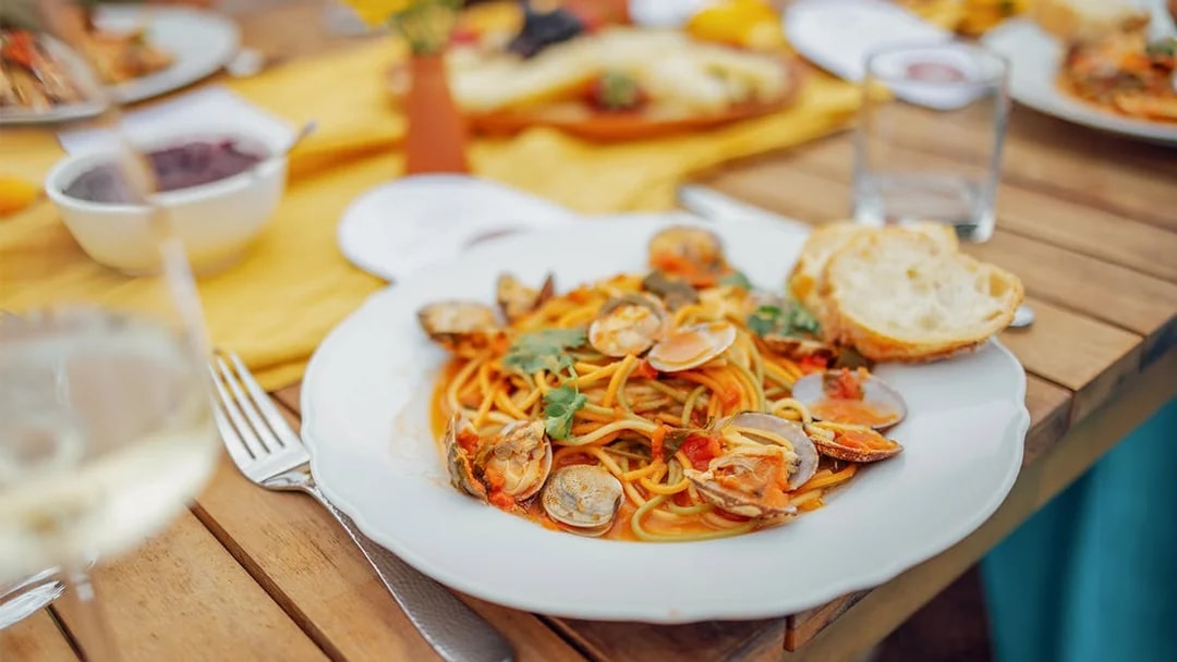 Seafood pasta dish on a wooden table during Cinque Terre tour from Florence.